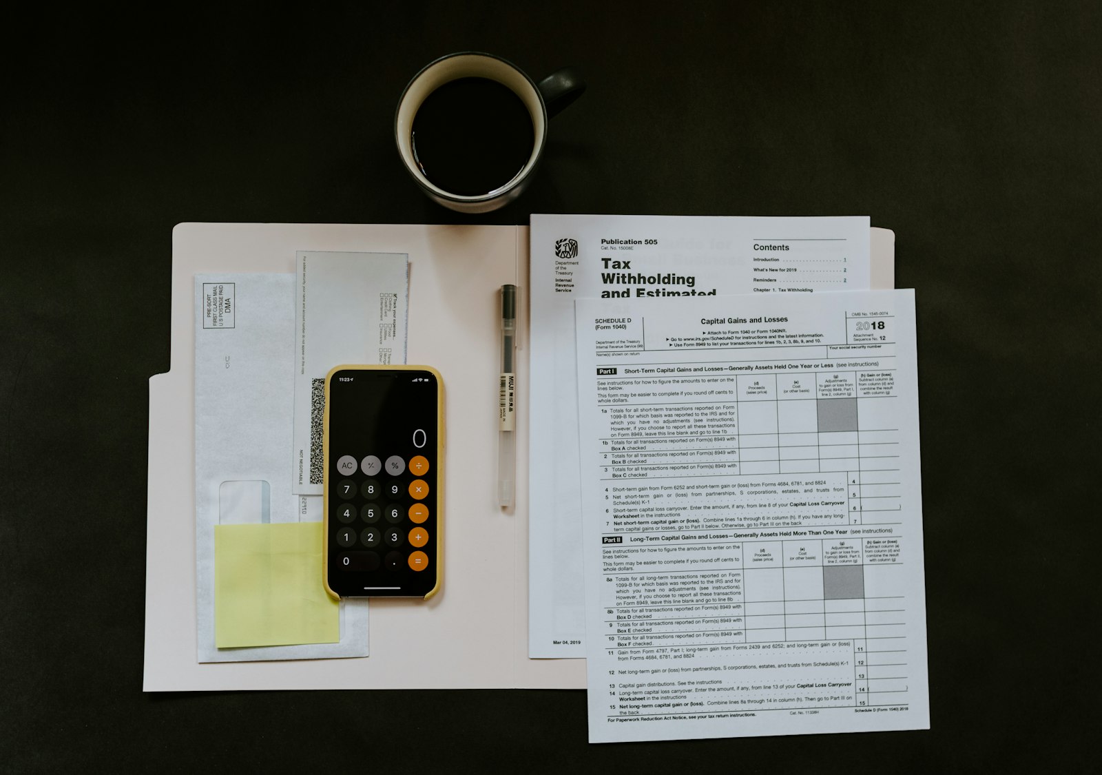 Phone, pen and tax forms on a folder